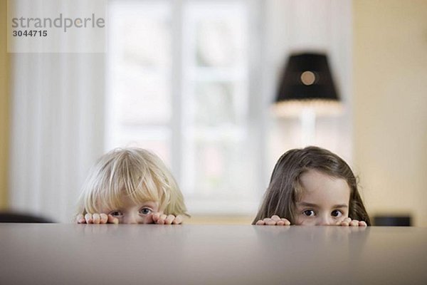 Kinder schauen über den Tischrand