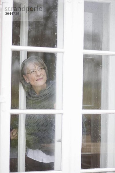 alte Frau  die aus dem Fenster schaut