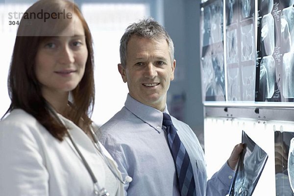Zwei Ärzte  lächelnd  mit Röntgenstrahlen im Hintergrund