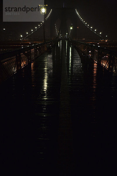 Fußgängerweg über die Brooklyn Bridge  nachts regennass  New York City  USA