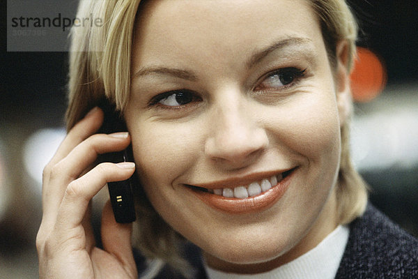 Frau telefoniert mit dem Handy lächelnd  seitwärts blickend  Portrait