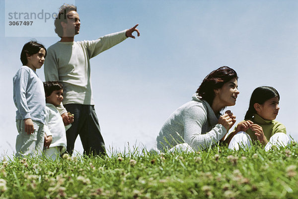 Familie zusammen im Grasfeld mit Blick auf die Umgebung
