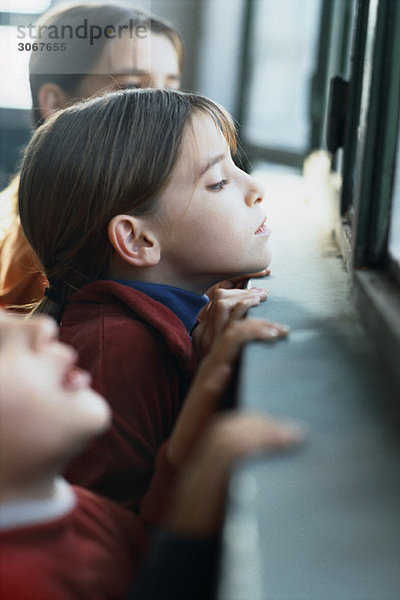 Kinder schauen über die hohe Fensterbank