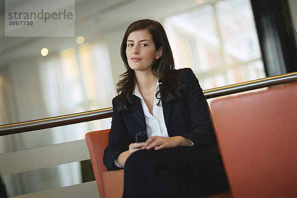 Geschäftsfrau sitzend mit Handy in der Hand  Portrait
