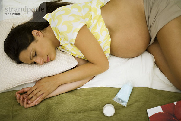 Müde schwangere Frau auf dem Bett liegend  ruhend
