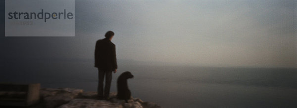 Personen- und Hundesilhouette vor dem Meer  Panoramablick