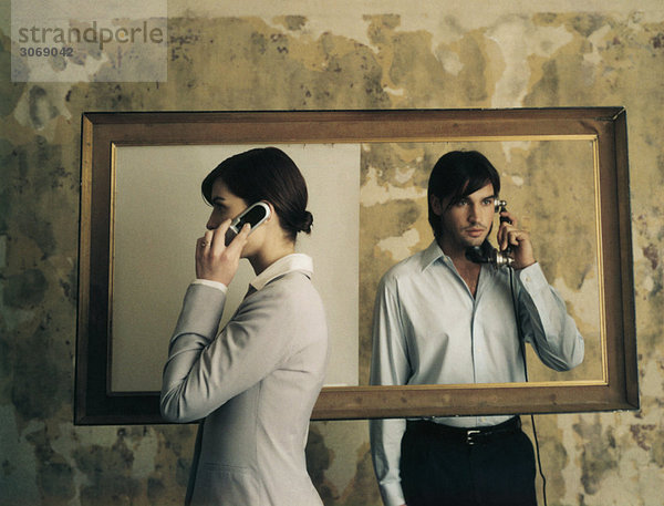 Auf beiden Seiten des Bilderrahmens stehend  Frau mit Handy und Mann mit altmodischem Festnetztelefon.
