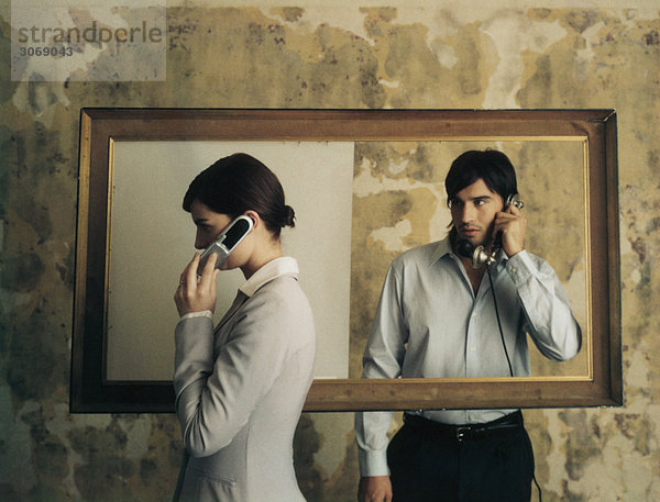 Stehend auf beiden Seiten des Bilderrahmens  Frau mit dem Handy  während der Mann mit dem altmodischen Festnetztelefon ihr zusieht