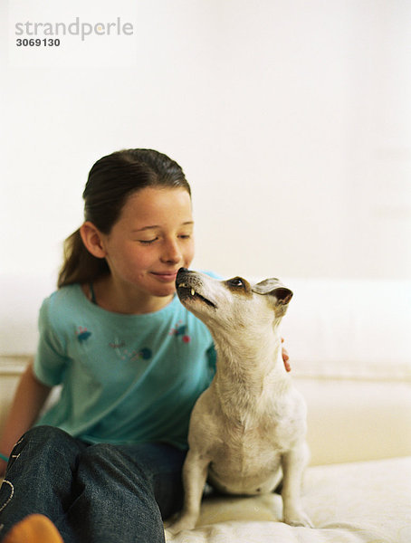 Mädchen sitzend auf Sofa mit Hund