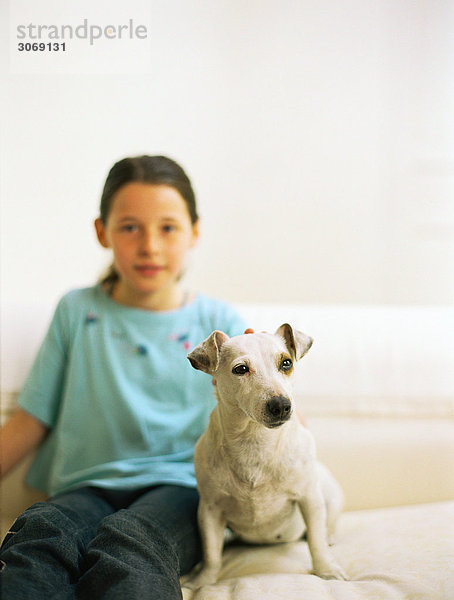 Mädchen sitzend auf Sofa mit Hund