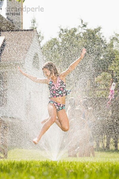 Mädchen springen in der Sprinkleranlage