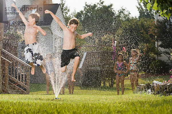 Kinder springen in der Sprinkleranlage