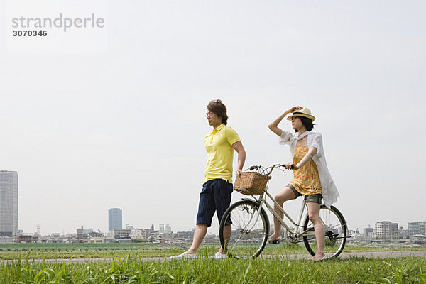 Junger Mann zu Fuß und junge Frau auf dem Fahrrad