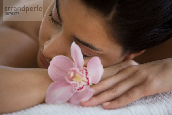 Junge Frau auf Massagetisch mit Orchideenblüten