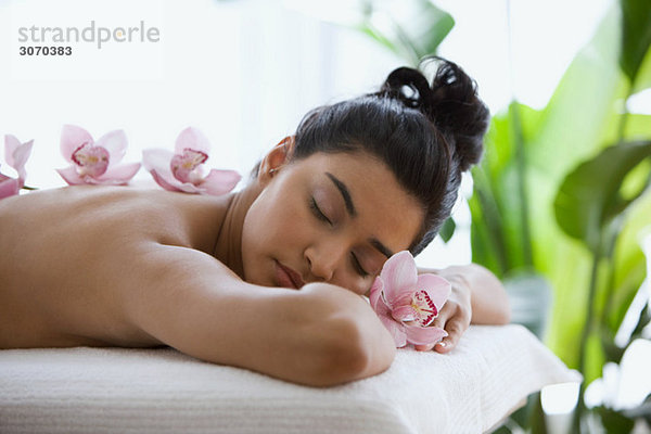 Junge Frau auf Massagetisch mit Orchideenblüten