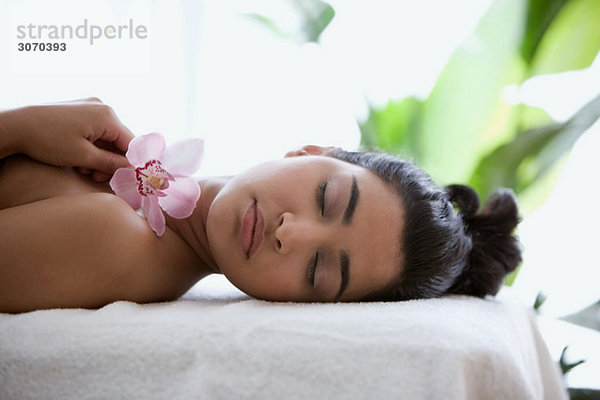 Junge Frau auf Massagetisch mit Orchideenblüten