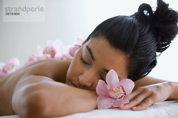 Junge Frau auf Massagetisch mit Orchideenblüten