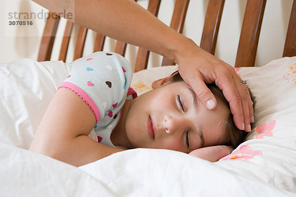 Schlafendes Mädchen mit erwachsener Hand auf dem Kopf