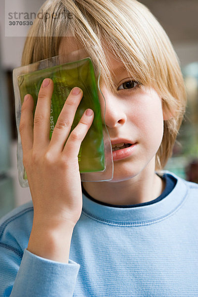 Junge mit Eisbeutel am Auge