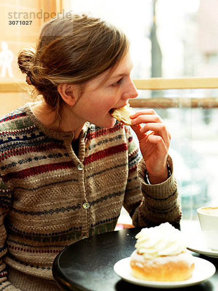 Junge Frau ein Stück Gebäck in einem Café Schweden Essen.