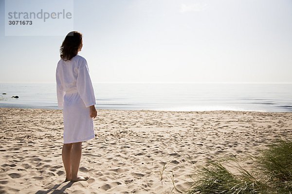 Frau an einem Strand in Bademantel Schweden gekleidet.