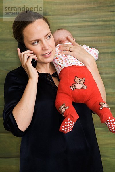 Eine Mutter halten ein Baby und ihr Handy Schweden