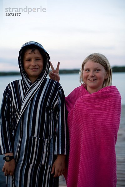 Two children wrapped in bathrobes on a jetty Sweden.