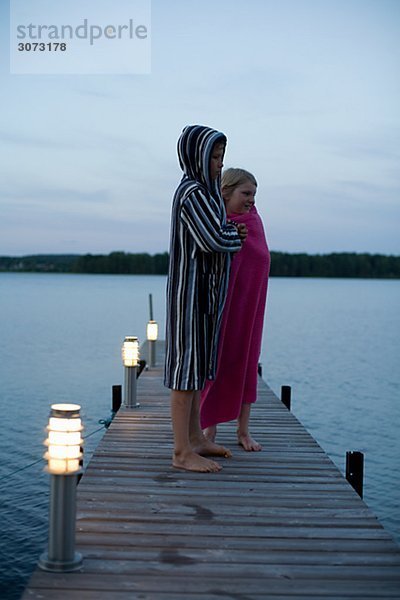 Two children wrapped in bathrobes on a jetty Sweden.