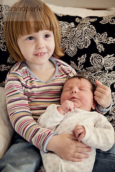 Girl holding her newborn baby sister in her arms Sweden.