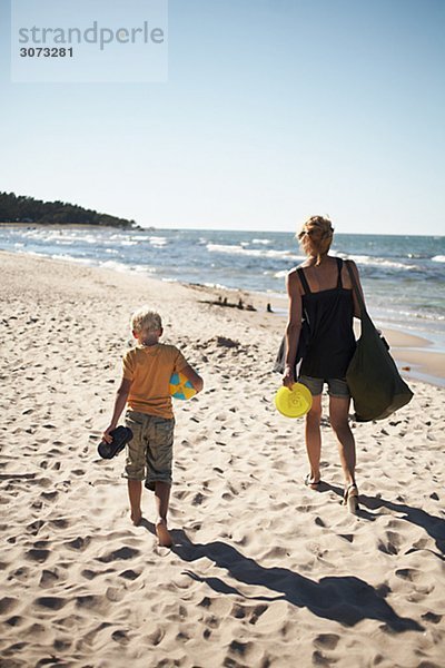 Mother and son walking on the beach Gotland Sweden.
