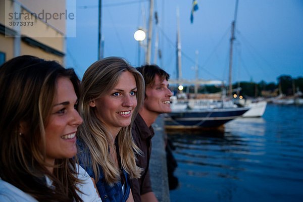 Three friends sitting on a quay-edge Stockholm Sweden.