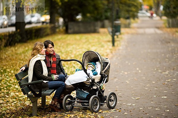 A couple siting with their son in a park Sweden.