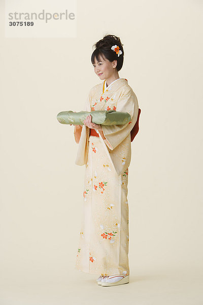 stehend Frau halten Kleidung Furoshiki Kimono