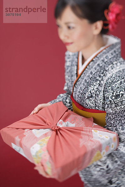 Frau in Kimono hält Furoshiki