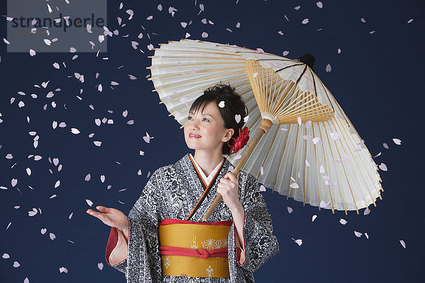Blütenblätter fallen auf Frau gekleidet in Kimono