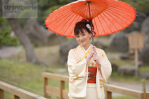 Frau gekleidet in Kimono Standing hält Parasol