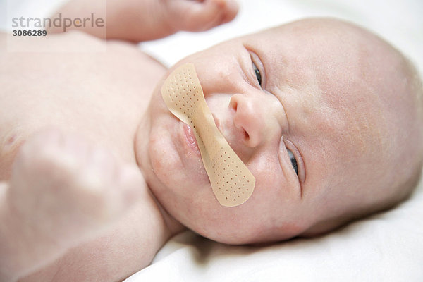 Männliches Baby mit Pflaster auf dem Mund  Close-up