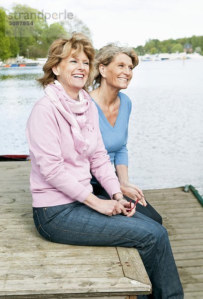 Zwei Freundinnen auf einem Pier sitzend