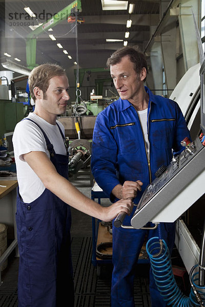 Zwei Arbeiter sprechen und arbeiten in einer Metallteilefabrik