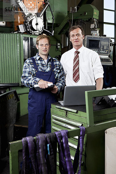 Ein Betriebsleiter und ein Fabrikarbeiter in einer Metallteilefabrik