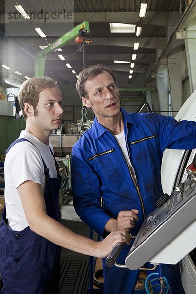 Zwei Arbeiter reden und arbeiten in einer Fabrik.
