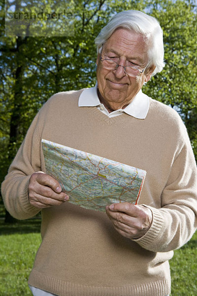 Ein älterer Mann  der sich eine Karte ansieht  draußen.