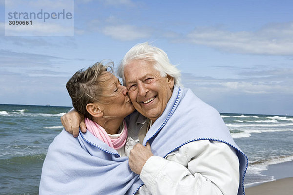 Ein älteres Paar  das zusammen am Strand spazieren geht.