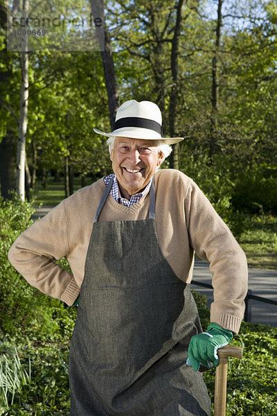 Ein älterer Mann  gekleidet für die Gartenarbeit  macht eine Pause.