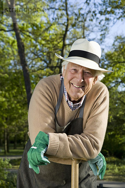 Ein älterer Mann  der eine Pause von der Gartenarbeit macht.