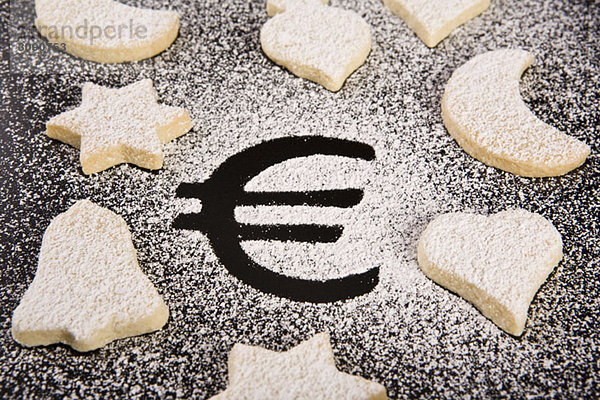 Das Euro-Symbol in Puderzucker umgeben von verschiedenen Gebäckformen
