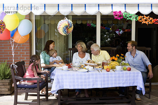 Eine Mehrgenerationen-Familie beim Frühstücken im Freien