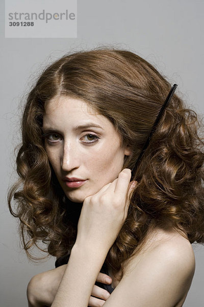 Porträt einer jungen Frau  die ihr Haar kämmt