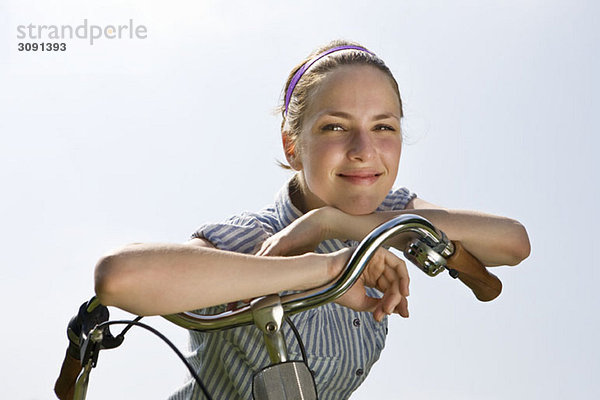 Eine junge Frau  die sich auf den Fahrradlenker stützt.