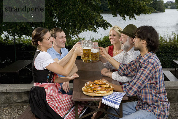 Fünf Personen in einem Biergarten Toastgläser